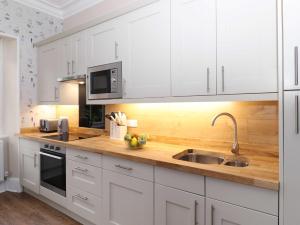 Redwood Rise Apartment Keswick في كيسويك: مطبخ مع دواليب بيضاء ومغسلة