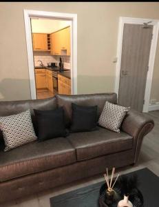 a brown couch in a living room with a kitchen at Large Three Bedroom Apartment with Roof Terrace Near City Centre in Cardiff