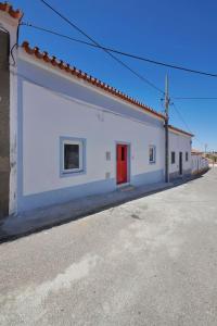 un bâtiment blanc avec une porte rouge dans une rue dans l'établissement Rustic & Aesthetic House in Alqueva with Pool, à Granja