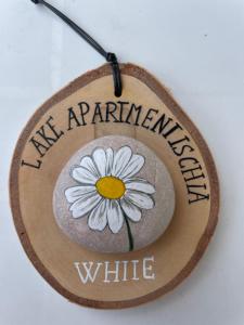 un cartel de madera con una margarita blanca. en Lake Apartment Ischia White, en Tenna 