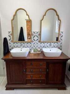 a bathroom with two sinks and two mirrors on a dresser at Stirling Cottage in Durban