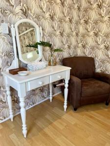 a white dressing table with a mirror and a chair at Stirling Cottage in Durban