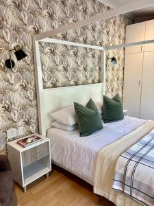 a bedroom with a bed with green pillows at Stirling Cottage in Durban