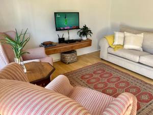 uma sala de estar com 2 sofás e uma televisão de ecrã plano em Stirling Cottage em Durban