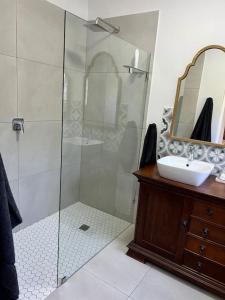 a bathroom with a shower and a sink and a mirror at Stirling Cottage in Durban