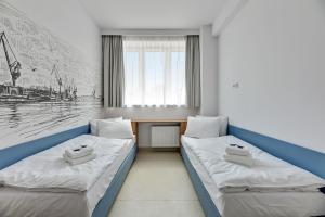 two beds in a room with a desk at Apartgdynia in Gdynia