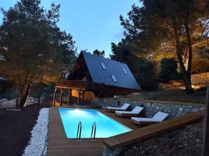 a pool in front of a barn with a house at Panurlawoodenhouse özel havuz& sauna mavi in Urla