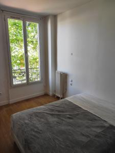 a bedroom with a bed and a large window at Le Palmier in Saint-Denis