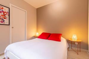 a bedroom with a white bed with two red pillows at Pleasant and bright chartreuse with terrace in Toulouse