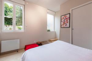 a bedroom with a white bed and two windows at Pleasant and bright chartreuse with terrace in Toulouse