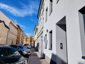 una calle con coches estacionados en el lateral de un edificio en Gemütliche Stadtwohnung in Klagenfurt en Klagenfurt