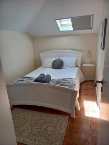a small bedroom with a white bed with a window at Casa Dos Ramos in Arco da Calheta