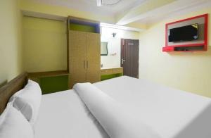 1 dormitorio con 1 cama y TV en la pared en POP Oyo Flagship Moon Light Hotel, en Ranchi
