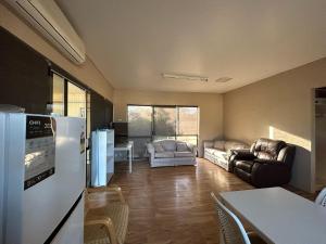 a kitchen with a refrigerator and a living room at East West Motel Ceduna in Ceduna