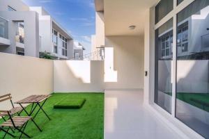 杜拜的住宿－Calm Aesthetic 3 Bedroom Villa - E&G Homes，一个带绿草和桌椅的庭院