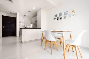 a white kitchen with a table and white chairs at Calm Aesthetic 3 Bedroom Villa - E&G Homes in Dubai