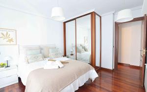 ein weißes Schlafzimmer mit einem großen Bett und einem Spiegel in der Unterkunft Coqueto apartamento en Liencres. in Liencres