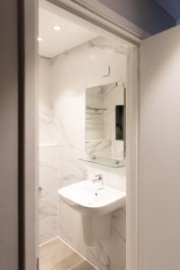 La salle de bains blanche est pourvue d'un lavabo et d'un miroir. dans l'établissement Princes Square, à Londres