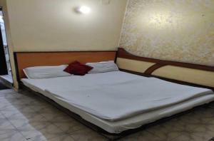 Una cama con sábanas blancas y un objeto rojo. en OYO Hotel Travel INN en Nueva Delhi
