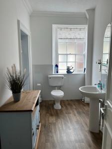 a bathroom with a toilet and a sink and a window at Stylish 2nd Floor Georgian 1 Bedroom Apartment in Dumfries