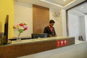 Ein Mann, der hinter einem Tresen in einem Büro steht. in der Unterkunft Capital O Bvh Hospitality Near Pvr Ansal Plaza Greater Noida in Noida