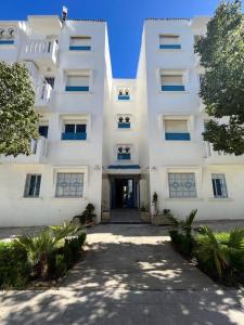 un immeuble d'appartements blanc avec une allée. dans l'établissement Charmant appart à 15 minutes de la plage et du centre ville M'DICQ, TETOUAN, à M'diq