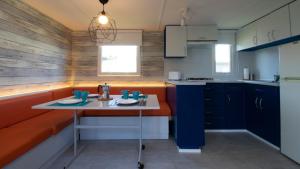 una cocina con armarios azules y una mesa. en Somo Bungalow Resort - Camping Latas, en Somo