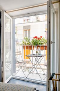 Une porte ouverte s'ouvre sur un balcon avec une table et des chaises. dans l'établissement Coreammare, à Naples