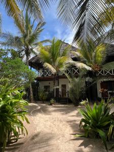 een huis met palmbomen ervoor bij The Seles Boutique Hotel in Matemwe