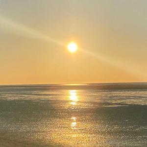 a sunset over the ocean with the sun setting at Amrum Family Hideaway-Grosse Wohnung in Norddorf für bis zu 6 Personen in Norddorf +3 photos