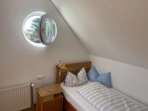 a small bedroom with a bed with a round window at Nolte Faarderhuuch 7 in Norddorf