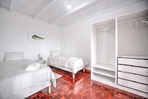 a white bedroom with two beds and a mirror at CASA do PÁTIO in Faja Grande