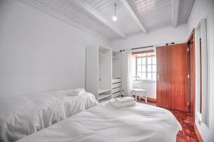 a white bedroom with two beds and a window at CASA do PÁTIO in Faja Grande