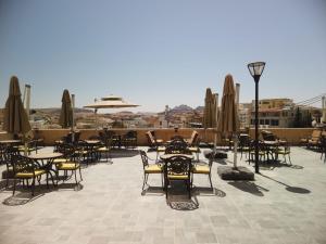 un patio esterno con tavoli, sedie e ombrelloni di H Luxury Hotel a Wadi Musa