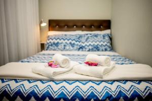 uma cama com toalhas brancas e flores cor-de-rosa em Casa dos Franz em Jaraguá do Sul