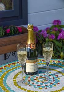 Una botella de champán y dos copas en una mesa. en Sunset View at The Dovecote en Kirkby on Bain