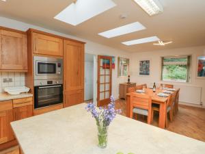 a kitchen with wooden cabinets and a table with purple flowers at Byewater in Ryde