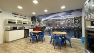 a kitchen with tables and chairs and a mural of a harbor at Casual Blue Bilbao in Bilbao