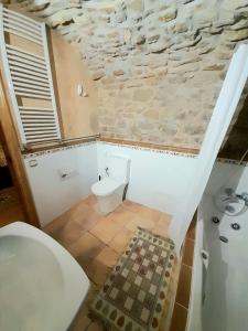baño con aseo blanco y pared de piedra en Casa San Anton en Valderrobres