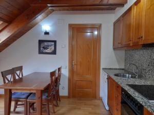 a kitchen with a wooden table and wooden cabinets at Apartamento abuhardillado con velux erta 3 in Pla de l'Ermita