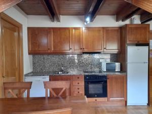 cocina con armarios de madera y nevera blanca en Apartamento abuhardillado con velux erta 3 en Pla de l'Ermita