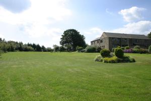 a large grass field with a building in the background at Ackroyd House in Holmfirth