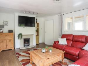 a living room with a red couch and a coffee table at Haddef Penmaenmawr in Penmaen-mawr