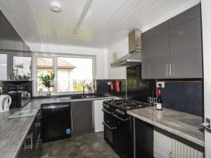 a kitchen with black appliances and a large window at Haddef Penmaenmawr in Penmaen-mawr