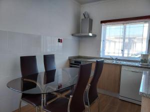 eine Küche mit einem Glastisch und Stühlen in der Unterkunft Casa Férias 