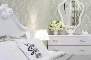 ein Schlafzimmer mit einem weißen Bett und einer Kommode mit einem Spiegel in der Unterkunft Красивая квартира в центре города с балконом in Odessa