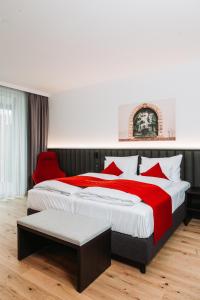 a bedroom with a large bed and a red chair at Hotel Das Grambacher 