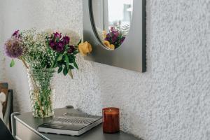 a vase of flowers on a table with a mirror at Apollo Resort in Agia Marina Aegina