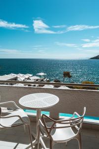 a patio with a table and chairs and the ocean at Apollo Resort in Agia Marina Aegina