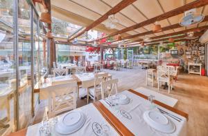Cinar Butik Hotel في كاس: مطعم بطاولات بيضاء وكراسي ونوافذ